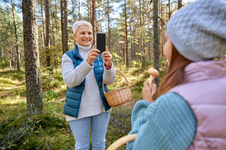 grandma photographing granddaughter with mushroomsの写真素材