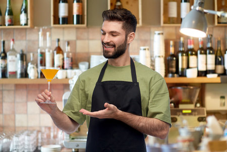 happy barman in apron with glass of cocktailの写真素材