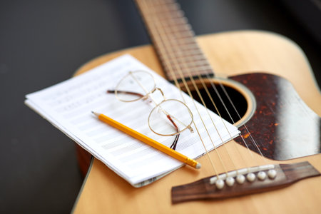 close up of guitar, music book, pencil and glassesの写真素材
