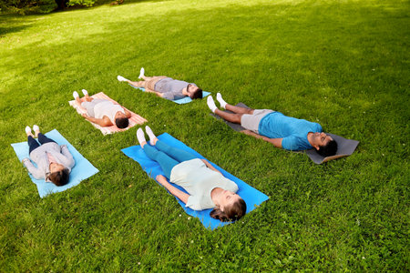 group of people doing yoga at summer parkの写真素材