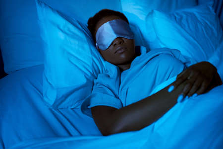 african woman sleeping in bed at home at night