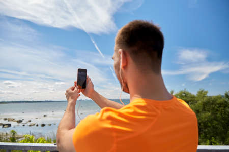 young man with smartphone and earphones outdoors
