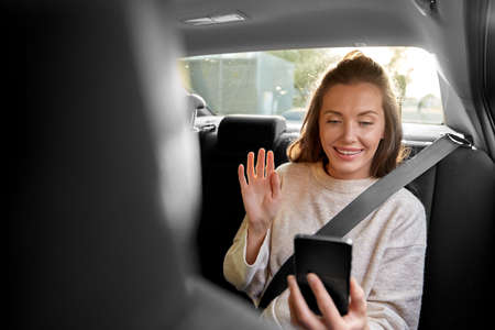 happy woman in car having video call on smartphone