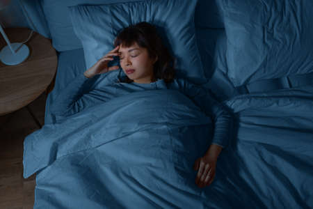 asian woman sleeping in bed at home at nightの写真素材