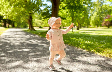 happy little baby girl walking in summer park