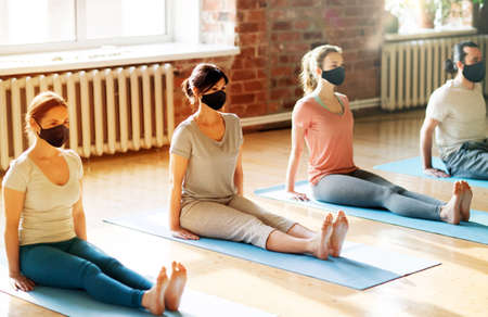 group of people in masks doing yoga at studio