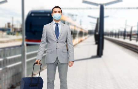 businessman in mask with travel bag over trainの写真素材