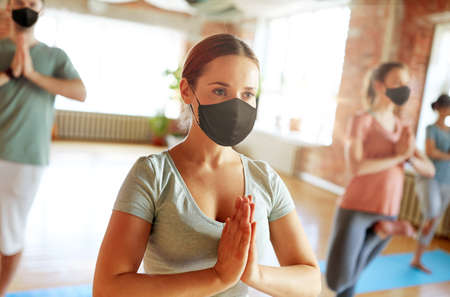 group of people in masks doing yoga at studioの写真素材