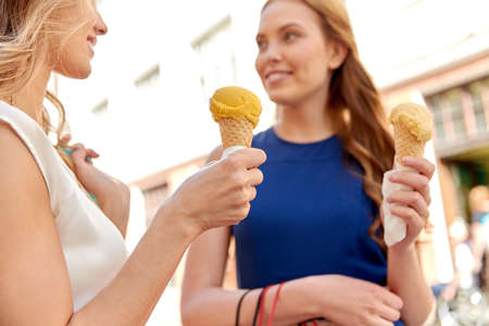 close up of happy women eating ice cream in city