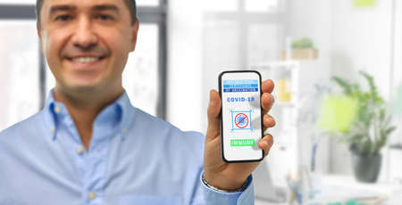 man with certificate of vaccination on smartphone