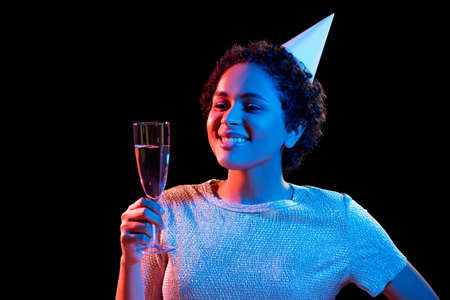 african woman in party cap with glass of champagne