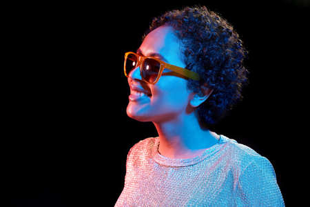 african woman in sunglasses over neon lights