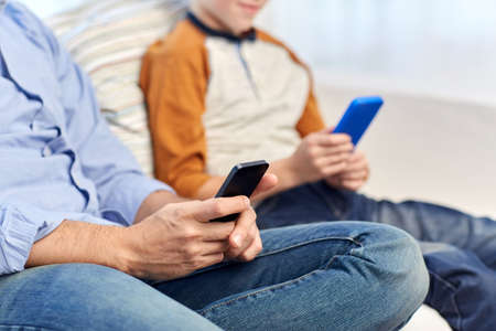 father and son with smartphones at home