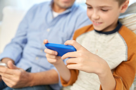 father and son with smartphones at home
