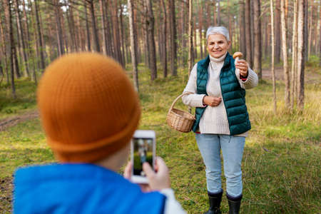 grandson photographing grandmother with mushroomの写真素材