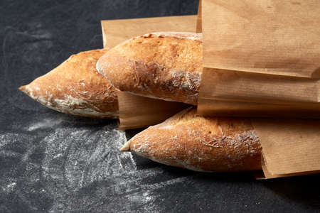 close up of baguette bread in paper bags on table