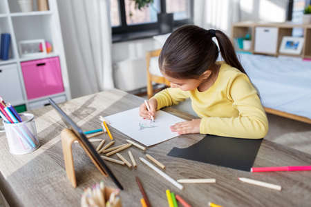 little girl drawing with coloring pencils at homeの写真素材