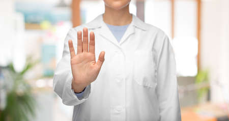 female doctor in white coat showing stop gesture