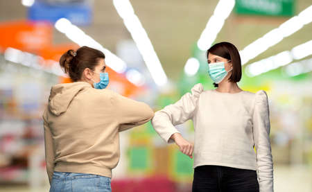 women in masks making elbow bump greeting gesture