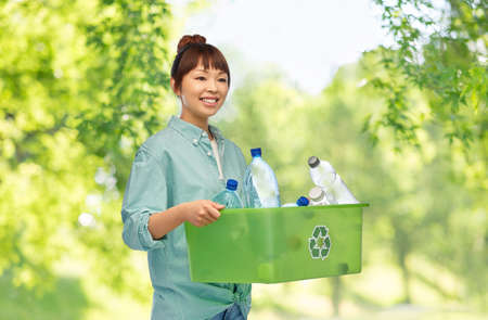smiling young asian woman sorting plastic wasteの写真素材