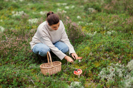 young woman picking mushrooms in autumn forest