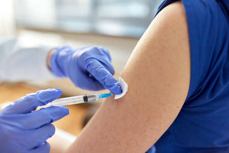doctor with syringe vaccinating medical workerの写真素材