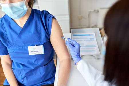 doctor with syringe vaccinating medical worker