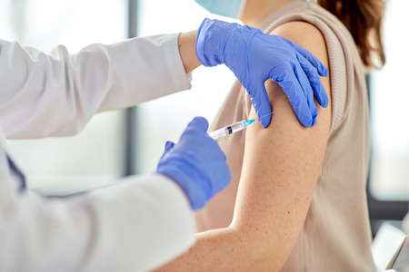 female doctor with syringe vaccinating patientの写真素材