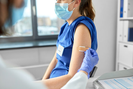 doctor attaching patch to medical workerの写真素材