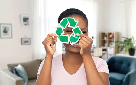smiling asian woman holding green recycling sign