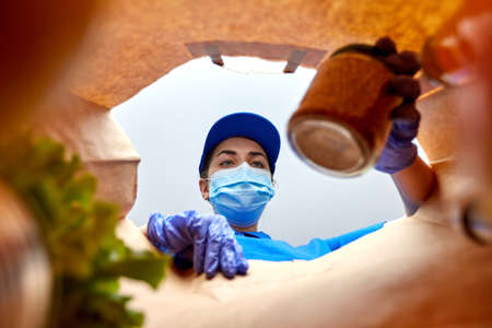 delivery girl in gloves and mask with food in bag