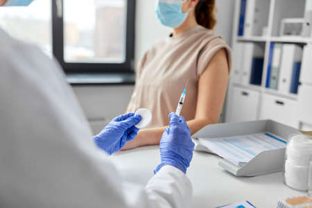 female doctor with syringe vaccinating patient