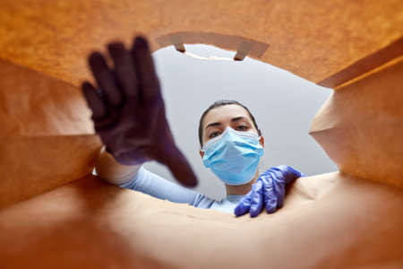 woman in gloves and mask with food in paper bag