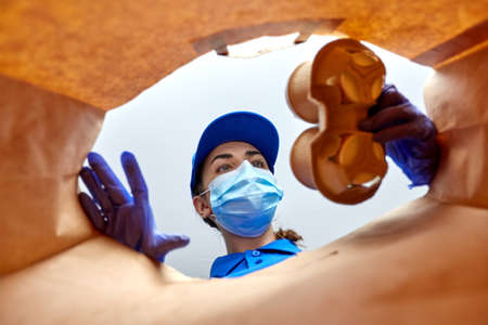 delivery girl in gloves and mask with food in bag
