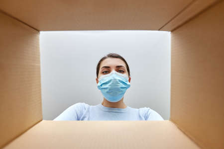 woman in mask looking inside cardboard parcel box