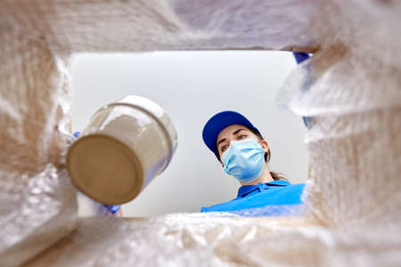 woman in mask packing flower pot to parcel box