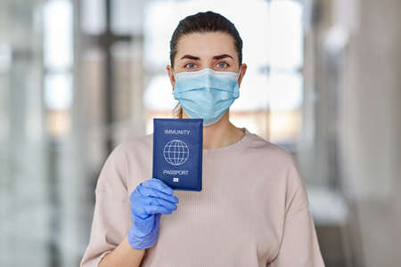 woman in mask and gloves holding immunity passportの写真素材