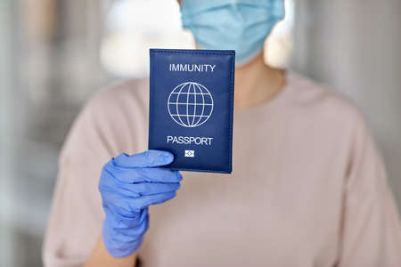 woman in mask and gloves holding immunity passportの写真素材