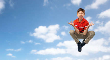 happy young boy flying in yoga pose over skyの写真素材