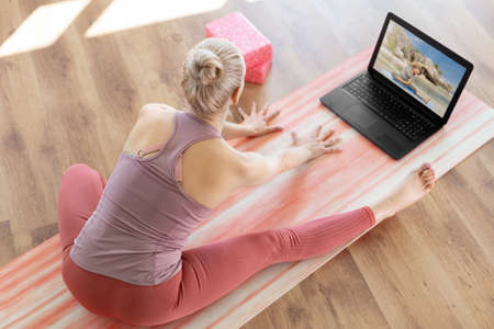 woman with laptop having online yoga class