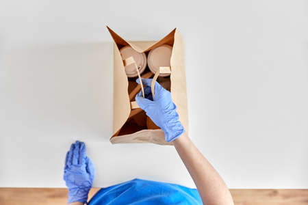 delivery woman in gloves packing food and drinks