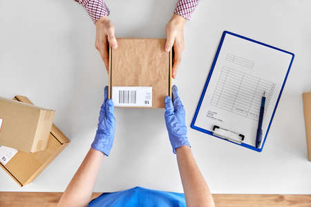 hands in gloves giving parcel box to customerの写真素材