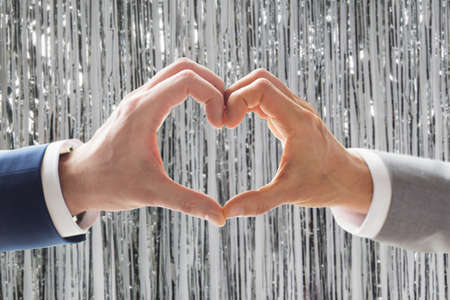 close up of male gay couple hands showing heart