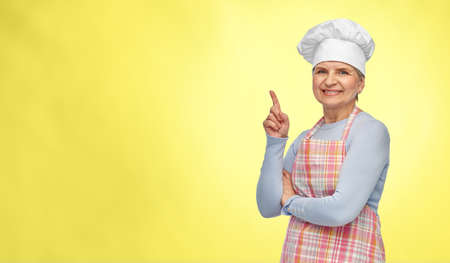 smiling senior woman or chef pointing finger upの写真素材