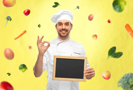 happy smiling male chef showing chalkboardの写真素材