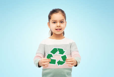 smiling girl holding green recycling sign on blue
