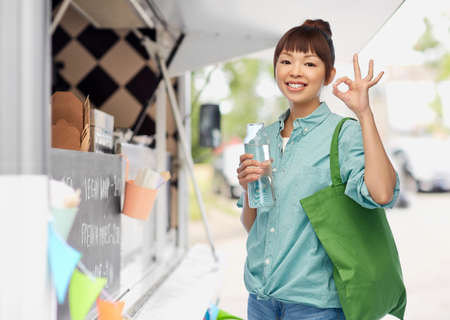 woman with shopping bag and bottle over food truckの写真素材