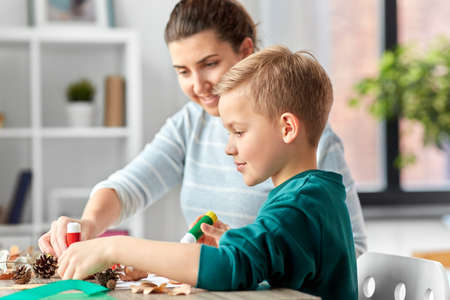 mother and son making pictures of autumn leavesの写真素材
