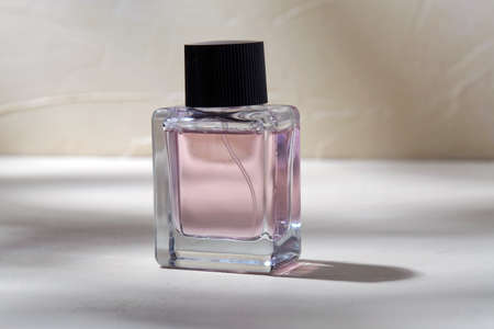 bottle of perfume on white surface with shadowsの写真素材