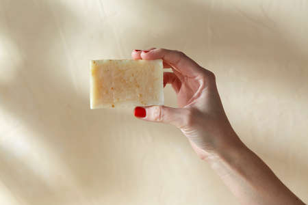 hand holding bar of craft soap on beige backgroundの写真素材